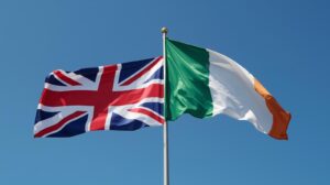The flags of the United Kingdom and Ireland waving together under a blue sky, symbolizing the new easier British citizenship route for Irish citizens